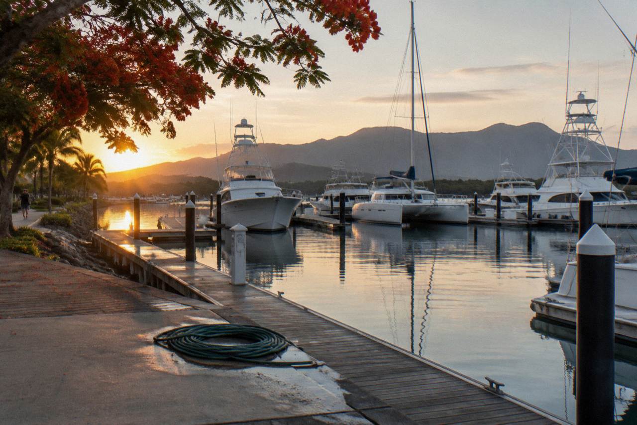Fishing boats moored at a tropical marina beside calm inlet water at sunrise
