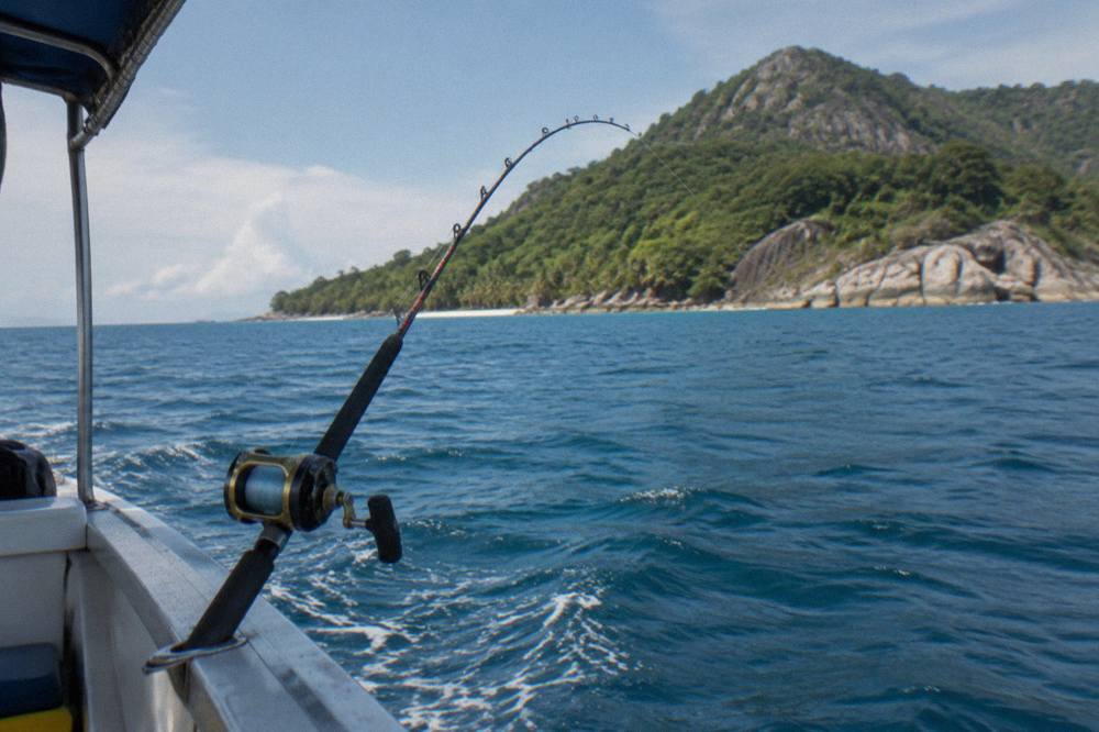 Heavy game fishing rod bent in a rod holder beside a game boat deck at sea