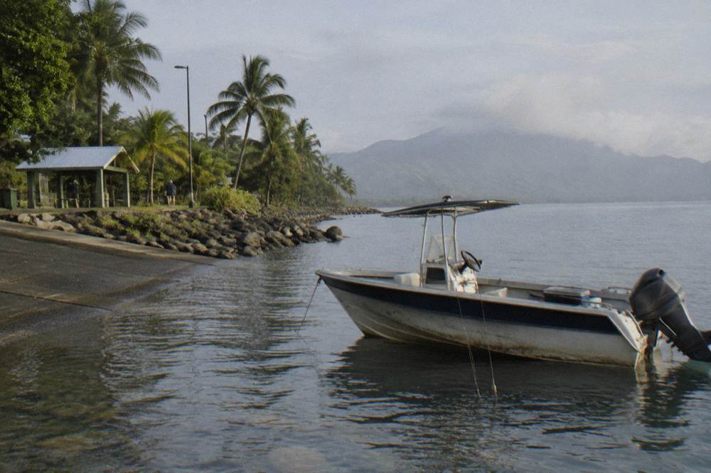 Small fishing boat anchored over a coral reef with handlines over the side