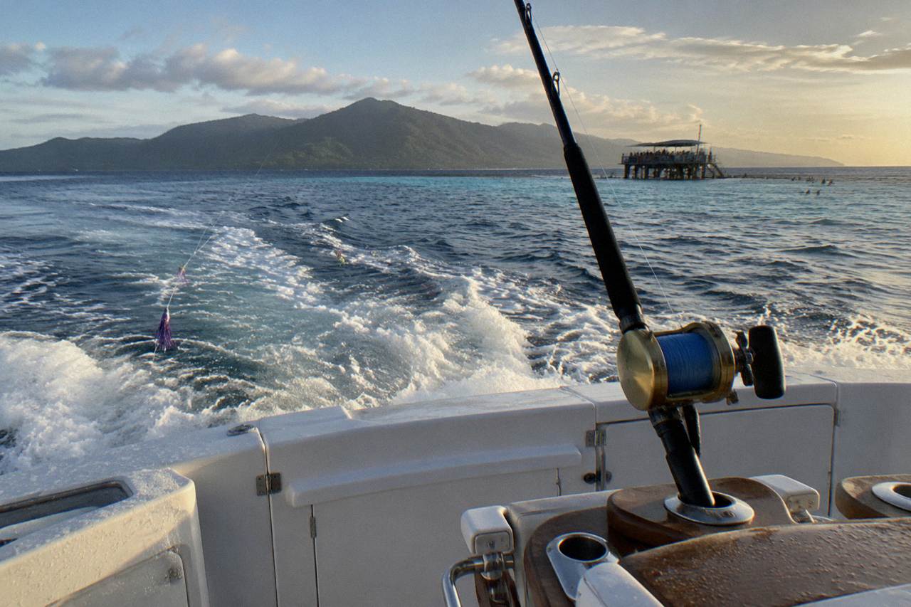 Game fishing boat cockpit with heavy tackle rod in a holder on a calm tropical sea