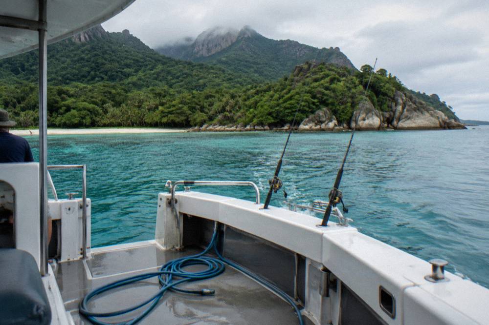 A small charter boat anchored over a coral reef with rods resting in holders