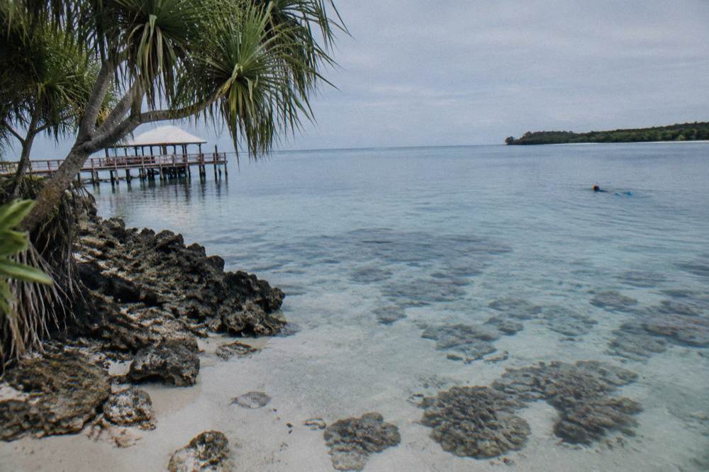 Calm reef water inside a sheltered cove with coral visible below the surface