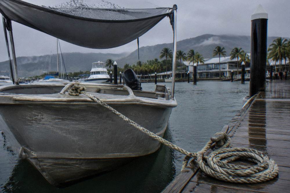 Small shaded tinnie boat moored at a tropical marina pontoon