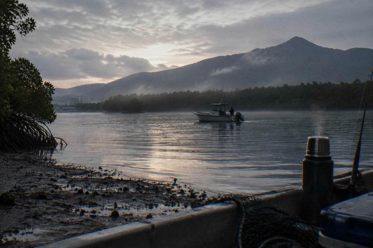 Small fishing boat on calm inlet water near mangroves at first light