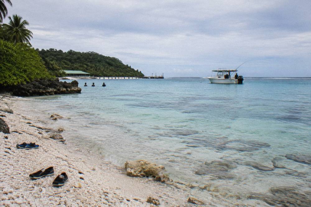 Reef fishing rod bent over the side of a small charter boat above clear tropical water