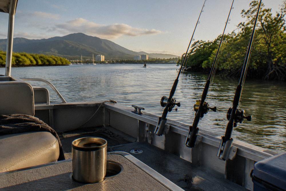 Small pontoon boat anchored in a calm mangrove inlet with fishing rods resting in holders