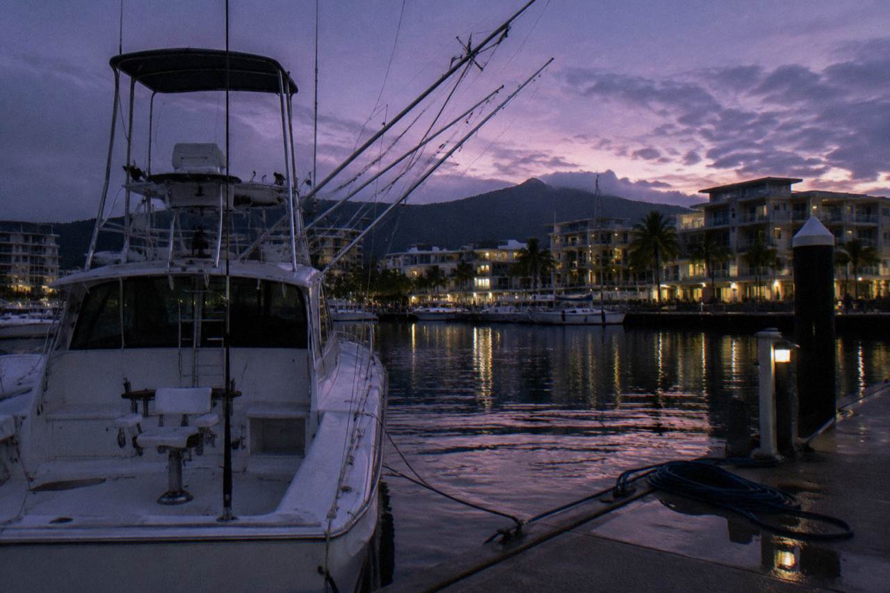 Game fishing tower and outriggers of a charter boat moored at a tropical marina at dawn