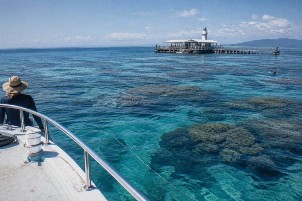 Clear blue water over a coral reef with scattered bommies and a hand line trailing from a boat