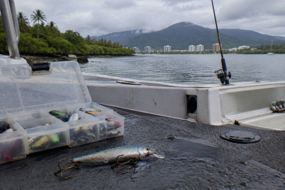 A hard-bodied lure resting on a boat deck beside a tackle box
