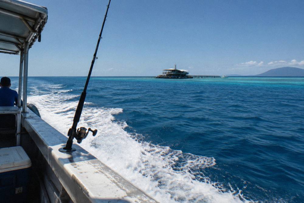 Game fishing boat running out to the outer reef in calm blue water