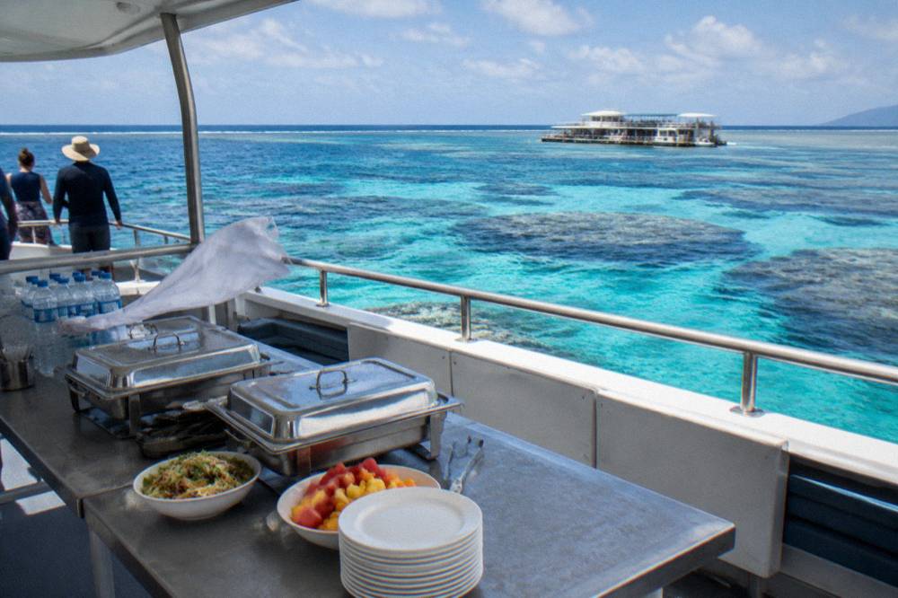 A buffet lunch laid out on the deck of a charter boat with covered dishes and water bottles