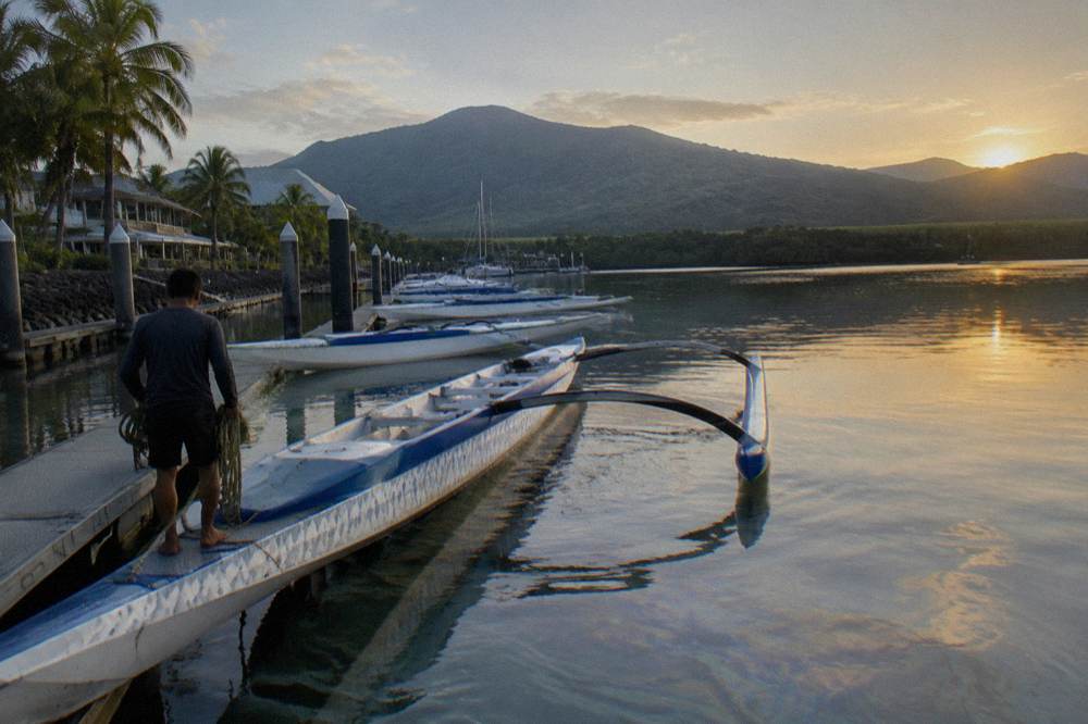 A game fishing boat with outriggers tied up at a tropical marina in early morning light