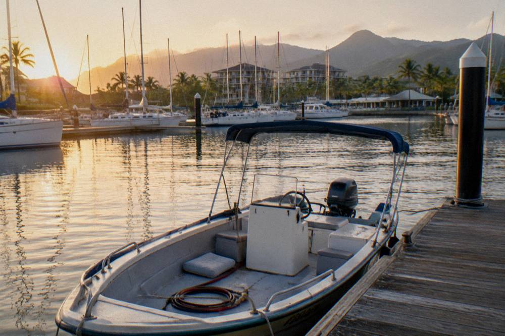 Small open fishing boat moored at a timber marina pontoon in morning light