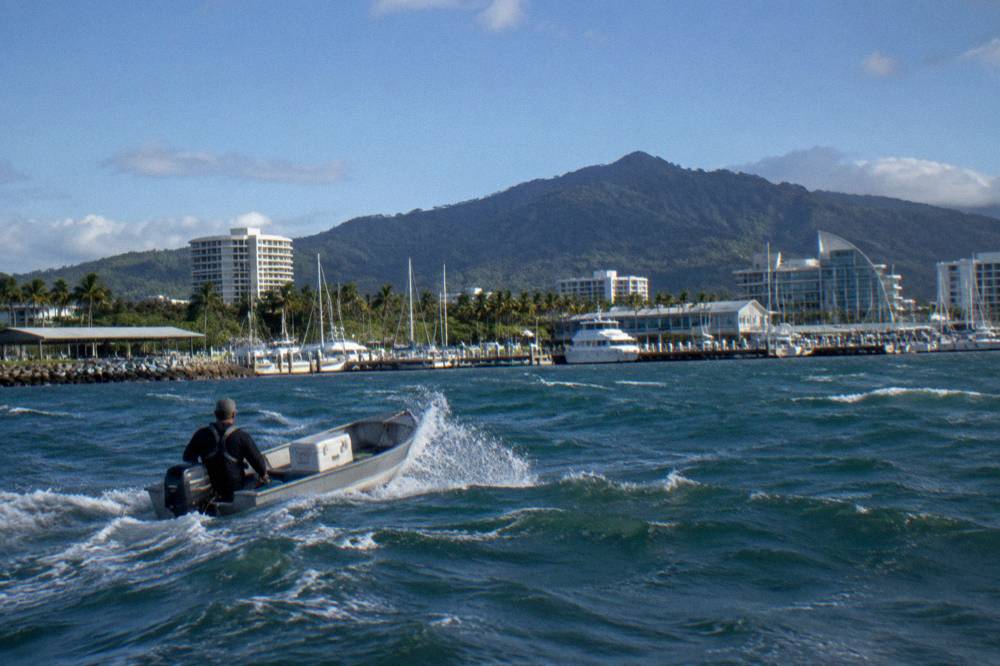 Small boat crossing open tropical water with whitecaps on the surface under a blue sky