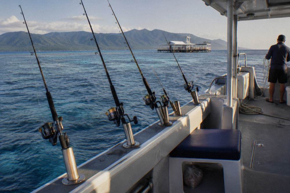 Rods in holders along the rail of a small charter boat over calm blue reef water