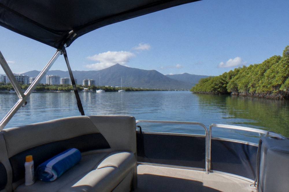 Shaded pontoon boat drifting on calm inlet water under a blue sky