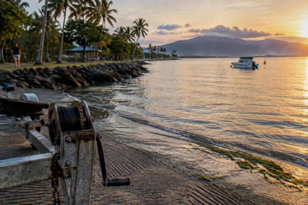 Weathered timber jetty over shallow tropical water in evening light