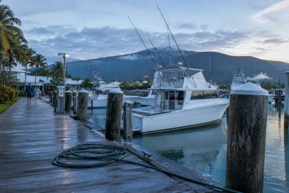 A marina boardwalk with moored fishing boats in early morning light
