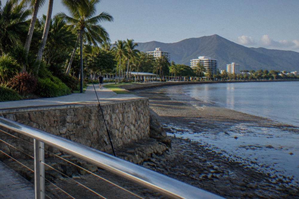 A safe distance back from a tropical waterway edge with fishing rod resting on a rock