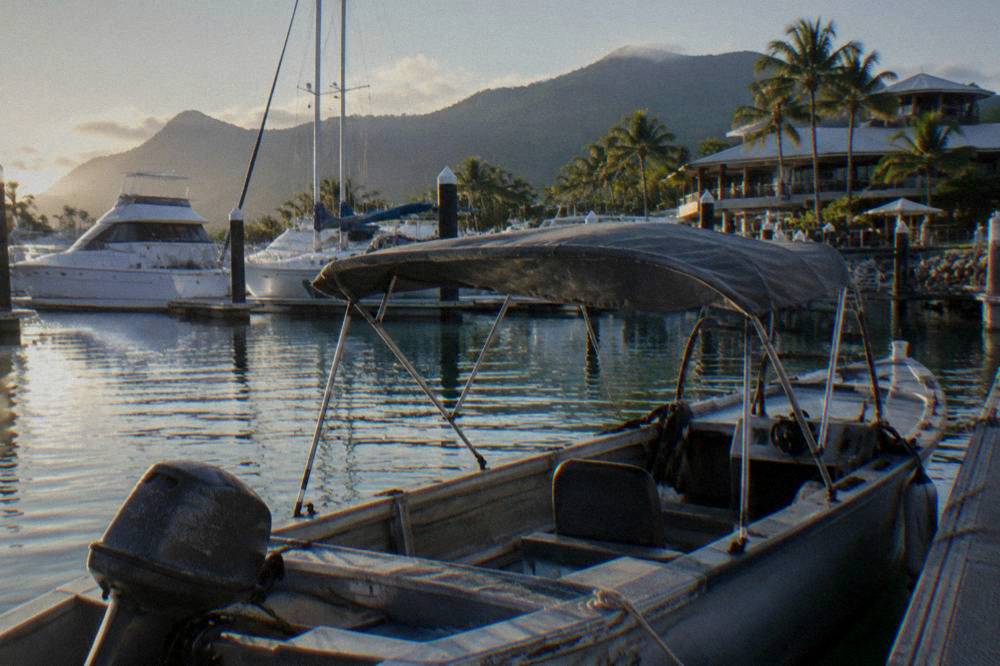 A small shaded tinny moored beside a tropical marina berth