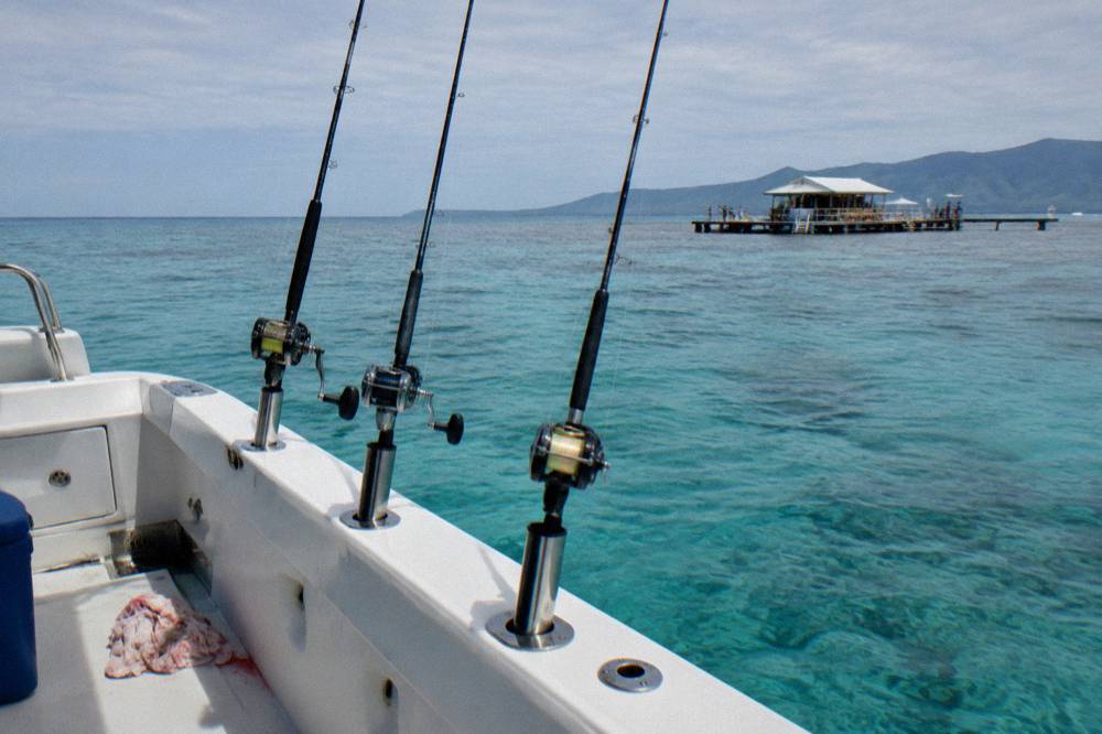 Charter boat deck with rods in holders and calm turquoise reef water beyond
