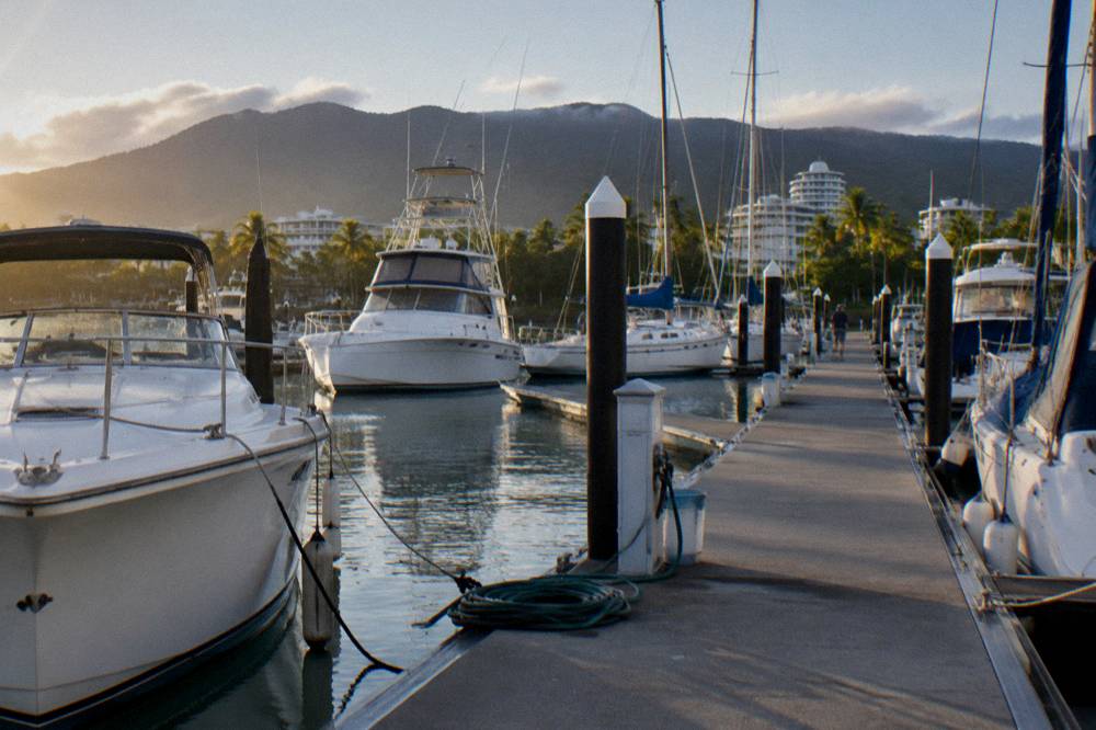 Morning light over a marina jetty with fishing charter boats moored alongside