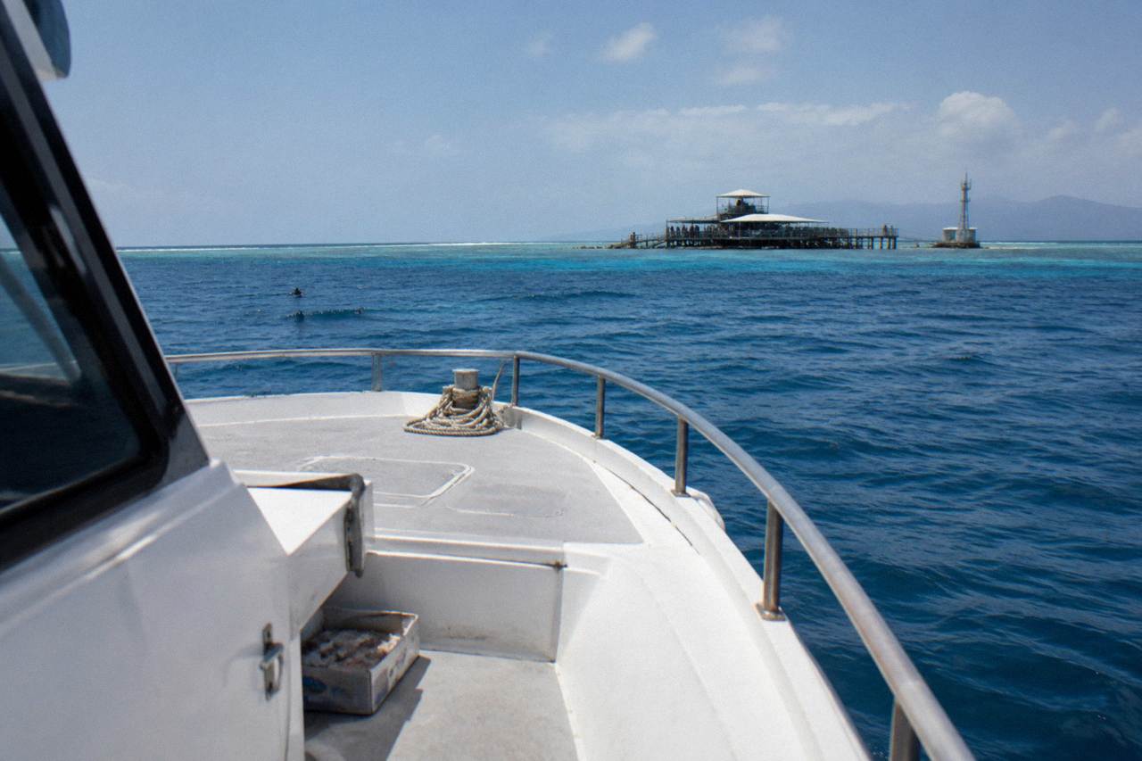 Fishing charter boat motoring across calm blue water toward reef grounds off Cairns