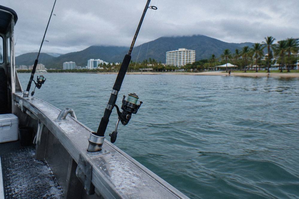 Rod holders on a boat deck with fishing rods rigged and ready over calm sea