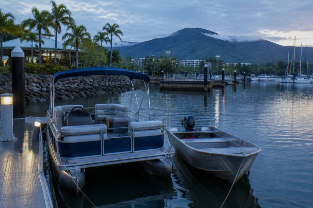 Small pontoon boat and tinny moored at a marina berth in the early morning