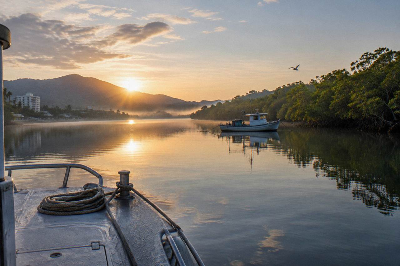 Small fishing boat anchored in a calm mangrove inlet at sunrise