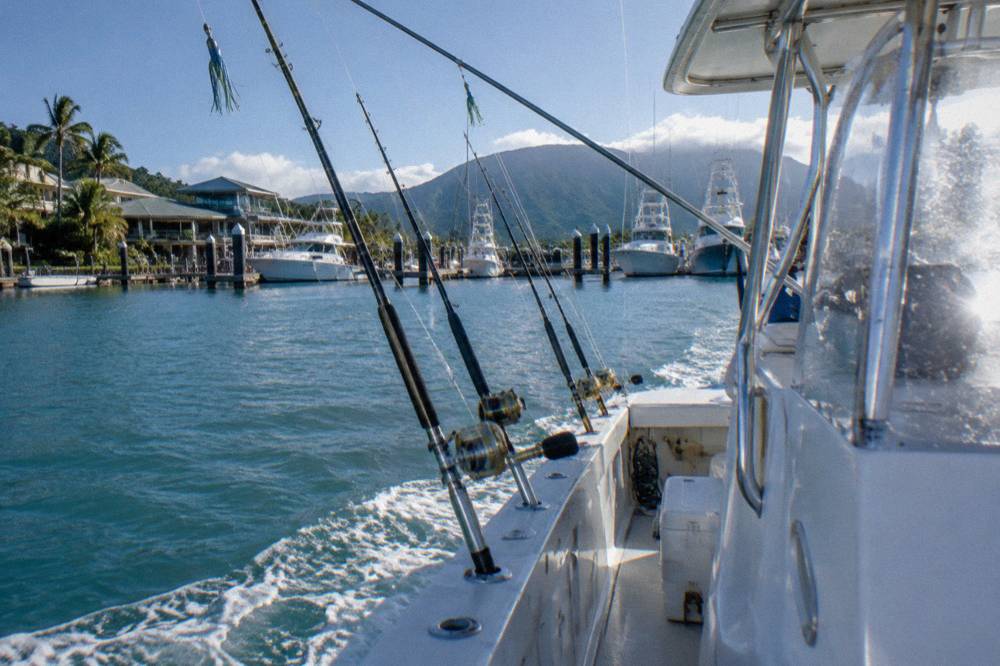 Outriggers and trolling rods set on a game fishing boat cruising past reef waters