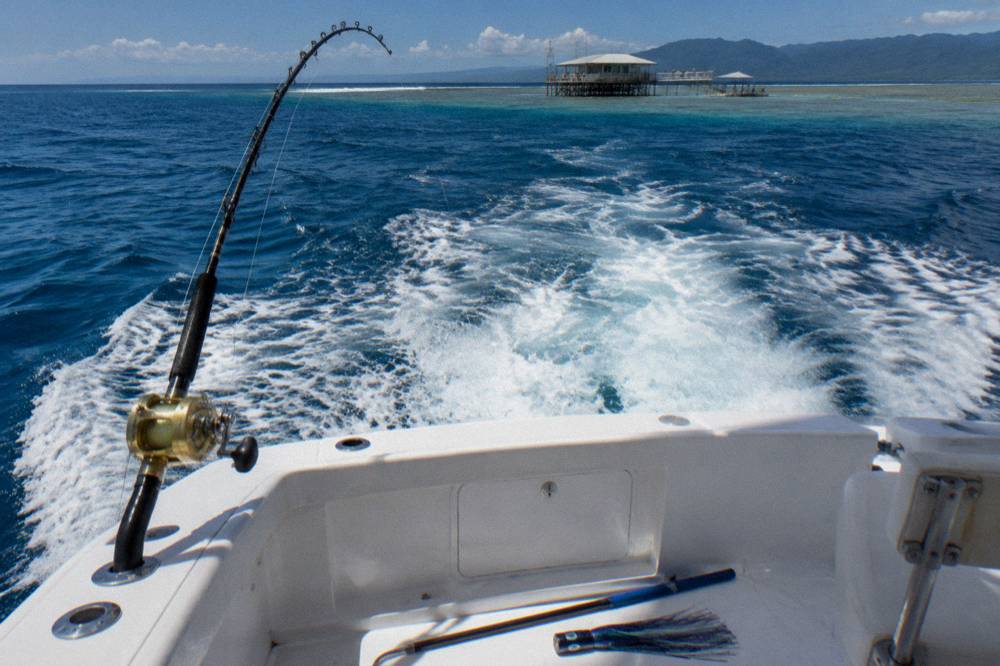 Heavy game fishing rod bent in a rod holder while a boat backs down on a fish