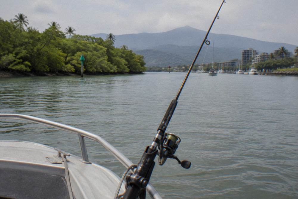 A spinning rod resting in a rod holder on the bow of a small boat