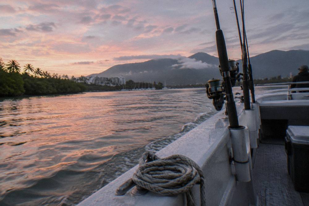 Charter boat rods in holders along the railing of a small river fishing vessel at dawn
